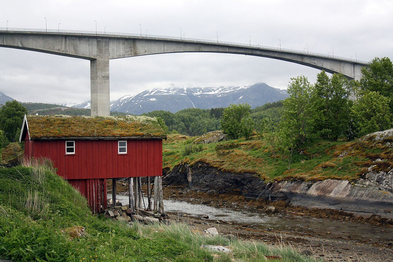 Saltstraumbrua sett fra land, med et rødt naust i forgrunnen